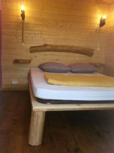 Cama pequeña en habitación de madera con 2 almohadas en camping Manex, en Saint-Pée-sur-Nivelle