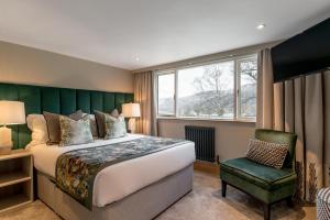a bedroom with a large bed and a chair at Borrowdale Gates Hotel in Keswick