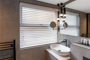 uma casa de banho com um lavatório e uma janela com persianas em Borrowdale Gates Hotel em Keswick