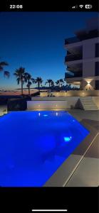 a blue swimming pool in front of a building at night at Primosten Resort Sunhill Deluxe Apartment Laura in Primošten