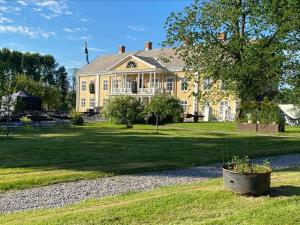 a large yellow house on a grass field with a tree at Sölje Herrgård Annexet in Glava