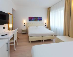 a hotel room with a bed and a desk and a bed at Hotel Mainè in Finale Ligure +29 photos