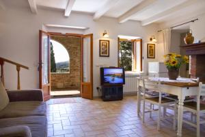 a living room with a television and a table and chairs at Poggio Cantarello Vacanze in Chiusi