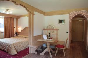 een slaapkamer met een bed en een bureau met een fles wijn bij Hotel Crepes de Sela in Campitello di Fassa