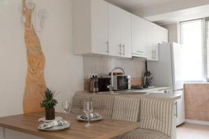 a kitchen with white cabinets and a wooden table with wine glasses at Modern Traditional apartment in Chişinău