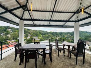 a patio with tables and chairs on a balcony at Mountain White Villa by Sunrise in Kandy