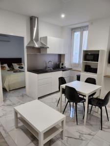 - une cuisine blanche avec une table, des chaises et un lit dans l'établissement Appartement dans le 8e arrondissement de Lyon (T2), à Lyon
