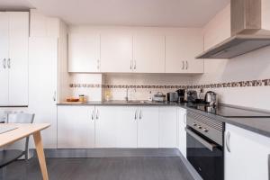 a white kitchen with white cabinets and a table at 2 Bed apartment near the beach with pool in El Campello