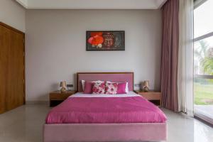 Un dormitorio con una cama grande con una manta morada. en StayVista La Paradise 2 BR villa With Outdoor Pool in Amritsar, en Amritsar