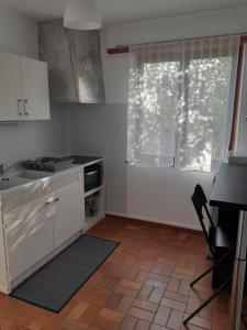 uma cozinha com armários brancos, um fogão e uma janela em Gîte Doux repos en campagne em Sundhoffen