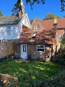 an old brick house with a yard with chairs at Adorable and Cosy Tiny Cottage in Heathfield