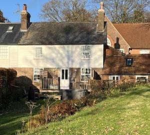 ein altes Backsteinhaus mit einer Veranda und einer Terrasse in der Unterkunft 3 bedroom Quirky Luxurious Cottage With Hot Tub in Heathfield