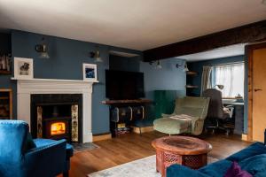 a living room with blue walls and a fireplace at 3 bedroom Quirky Luxurious Cottage With Hot Tub in Heathfield