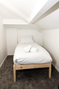 a bed in a small room with white sheets at Suite 7 - Family Room in the Heart of Oldham in Oldham
