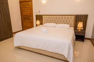 a bedroom with a large white bed with two lamps at Kings Hantana in Kandy