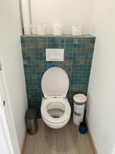 a bathroom with a toilet with a green tiled wall at Appartement Plage Prado avec parking in Marseille