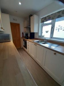 a kitchen with white cabinets and a sink and a window at No. 6 The High Street in Royal Wootton Bassett