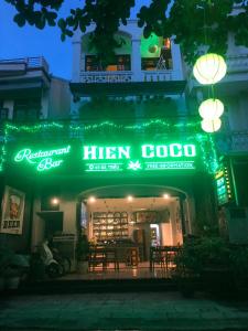 um restaurante com um sinal verde de néon à noite em Hien CoCo Homestay Hoi An em Hoi An