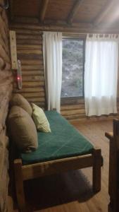 1 cama en una cabaña de madera con ventana en Balcones del Portezuelo en Potrerillos