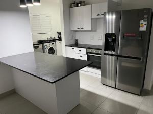 a kitchen with a stainless steel refrigerator and white cabinets at The Lonely Mountain in Mataffin