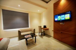 ein Wohnzimmer mit einem TV, einem Sofa und einem Tisch in der Unterkunft Hotel Stanley- Near Delhi Airport in Neu-Delhi