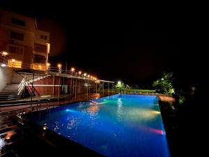 a large blue swimming pool at night with a building at Ivy Park Resort in Panchgani