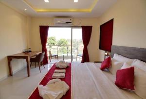 a bedroom with a large bed with a desk and a window at Ivy Park Resort in Panchgani