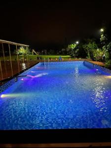 een groot zwembad van blauw water in de nacht bij Ivy Park Resort in Panchgani
