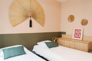 ein Schlafzimmer mit 2 Betten und einem großen Ventilator an der Wand in der Unterkunft L'atelier de Luc, Paris 20eme in Paris