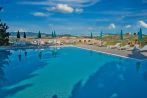 a large blue swimming pool with chairs and umbrellas at Agriturismo Biologico Diacceroni in Villamagna