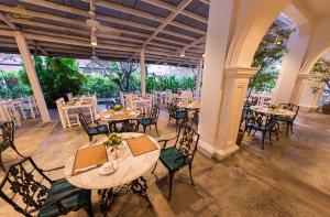 a dining room with tables and chairs and a large window at The Old Phuket - Karon Beach Resort - SHA Plus in Karon Beach