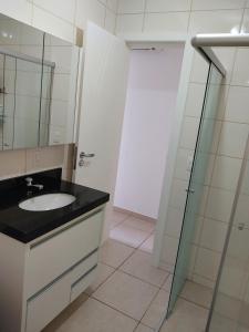 un bagno con lavandino e doccia in vetro di Suíte confortável para casal ou 2 mulheres a Balneário Camboriú