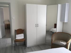 ein Zimmer mit einem großen weißen Schrank mit einem Stuhl und einem Spiegel in der Unterkunft Maison 4 pers à 5kms de la plage in Plouider