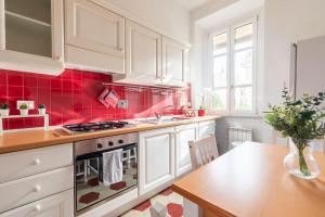 uma cozinha com armários brancos e azulejos vermelhos em G & G Maisonette Testaccio em Roma