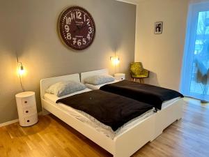 1 dormitorio con 1 cama con reloj en la pared en Moderne Neubauwohnung bei Köln en Lindlar