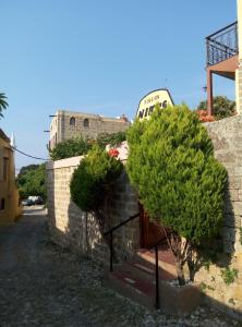 a stone wall with two trees and a building at Niki's Pension in Rhodes Town