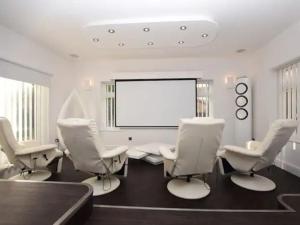 a conference room with white chairs and a projection screen at Eastfield Lodge with Hot Tub in Stannington