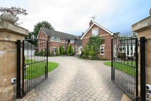 a gate to a brick house with a driveway at Eastfield Lodge with Hot Tub in Stannington