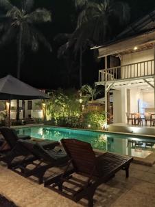 einen Pool in der Nacht mit zwei Stühlen und einem Sonnenschirm in der Unterkunft White Coconut Resort in Gili Trawangan