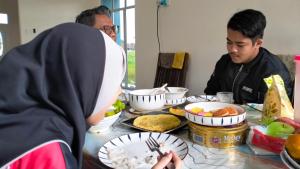 een groep mensen aan een tafel met eten bij Homestay Dena Moon Inn in Tumpat