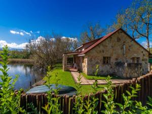 a stone house next to a lake at Lake Naverone Holiday Cottages in Drakensberg Garden