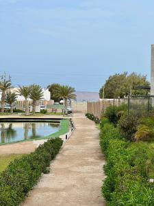 um caminho de terra junto a uma piscina de água em 2BR Apartamento Moxie Paracas con Terraza y AC en 1r Piso em Paracas