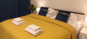 Central Cracow Apartments في كراكوف: غرفة نوم بسرير اصفر عليها مناشف
