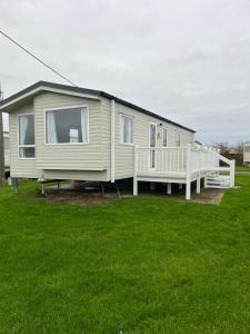 a mobile home with a porch on a grass field at Ingoldmells Honeybee Fantasy Island in Lincolnshire