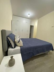 Schlafzimmer mit einem Bett mit blauer Bettwäsche und Kissen in der Unterkunft Departamento de Estreno SEMREQ in Piura