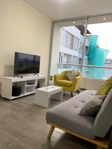- un salon avec une télévision, un canapé et une chaise dans l'établissement Departamento de Estreno SEMREQ, à Piura