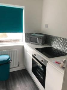 a small kitchen with a stove and a microwave at Vibrant 1st Floor Apartment in Cramlington
