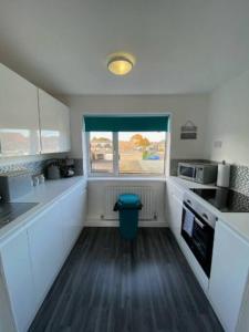 a kitchen with white cabinets and a blue trash can at Vibrant 1st Floor Apartment in Cramlington