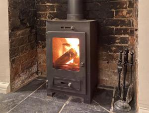 a wood stove in a room with a brick wall at Shardlow Cottage in Derby