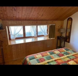 a bedroom with a bed and windows in a cabin at Appartamento Abetone Vacanze in Abetone